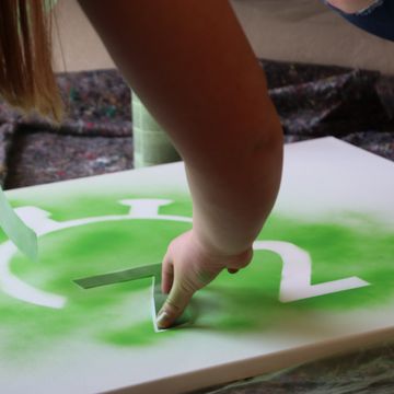 Eine Person entfernt die Schablone, mit der das Logo der Aktion gesprüht wurde.